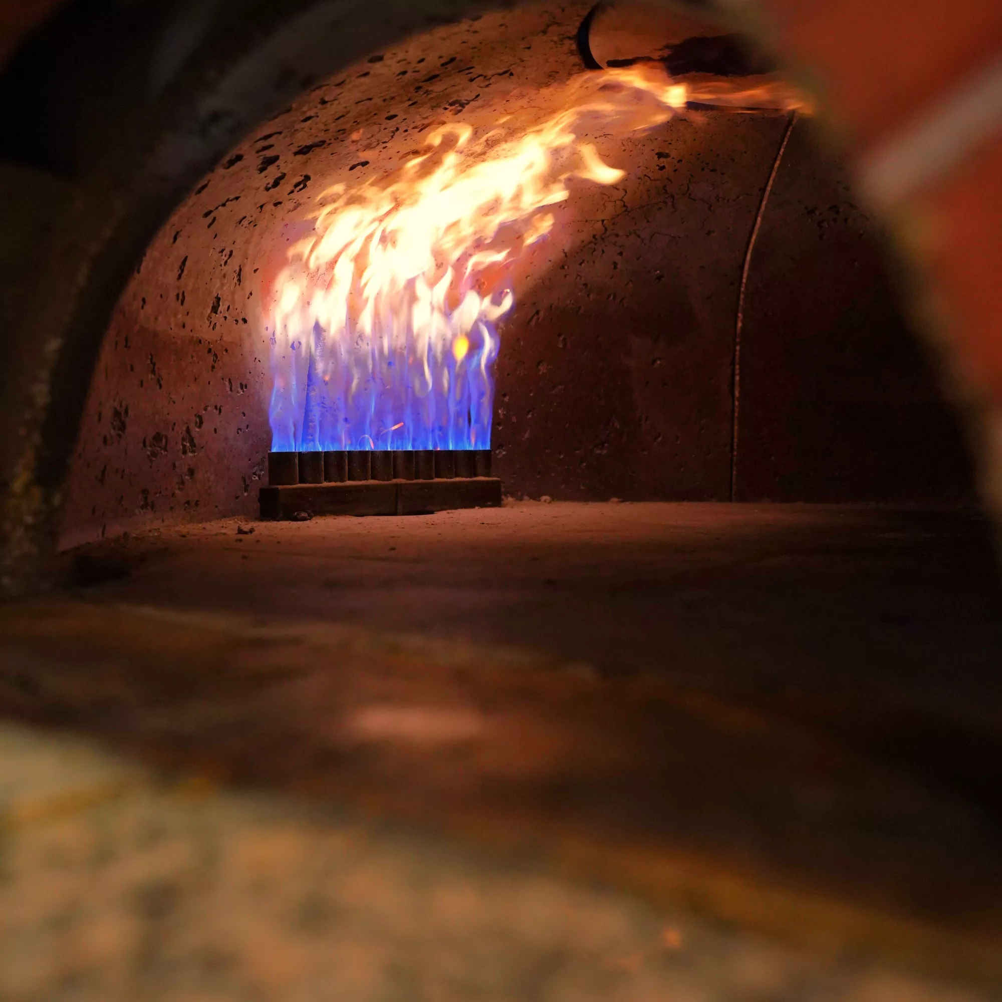 <think> Got it, let's create the alt text. The image shows a brick oven with flames inside. Need to describe what's visible…