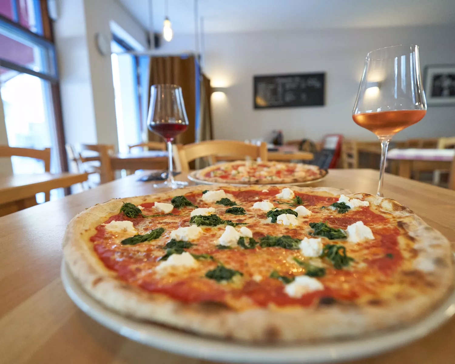 <think> Got it, let's create the alt text. First, identify what's visible. The main elements are two pizzas on a wooden tabl…