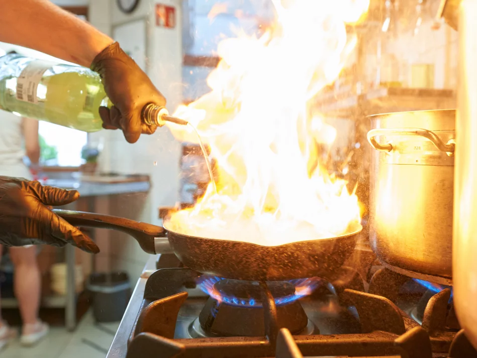 <think> Got it, let's create the alt text. The image shows a person in a kitchen pouring liquid from a bottle into a frying…