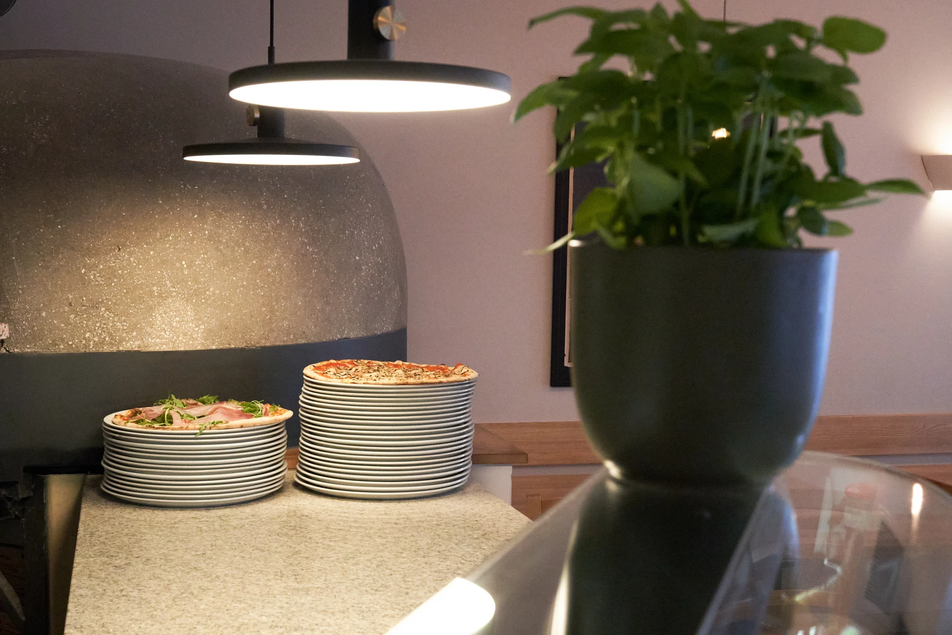 <think> Got it, let's create the alt text. First, identify what's visible. There's a large stone oven, two stacks of plates…
